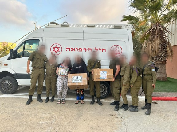 חייילים מקבלים חבילות מאחוריהם ניידת